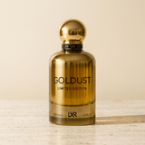 Goldust Limited Edition gold perfume bottle on pale stone against a warm cream background.